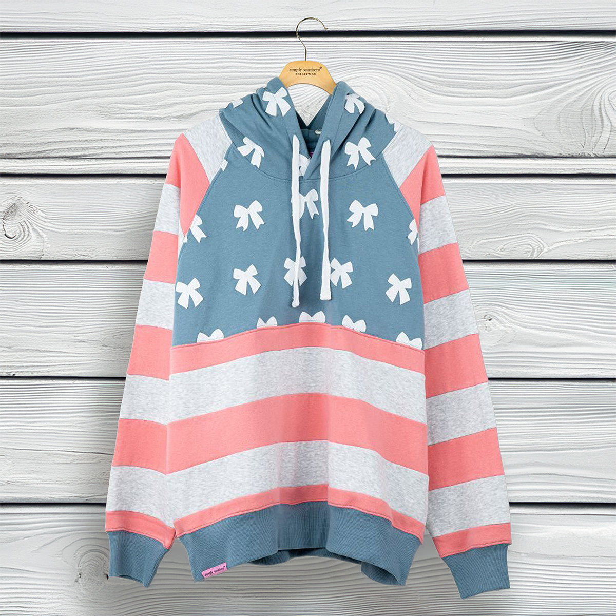 Simply Southern women’s pullover hoodie with white bow pattern, blue hood, and coral and gray striped sleeves