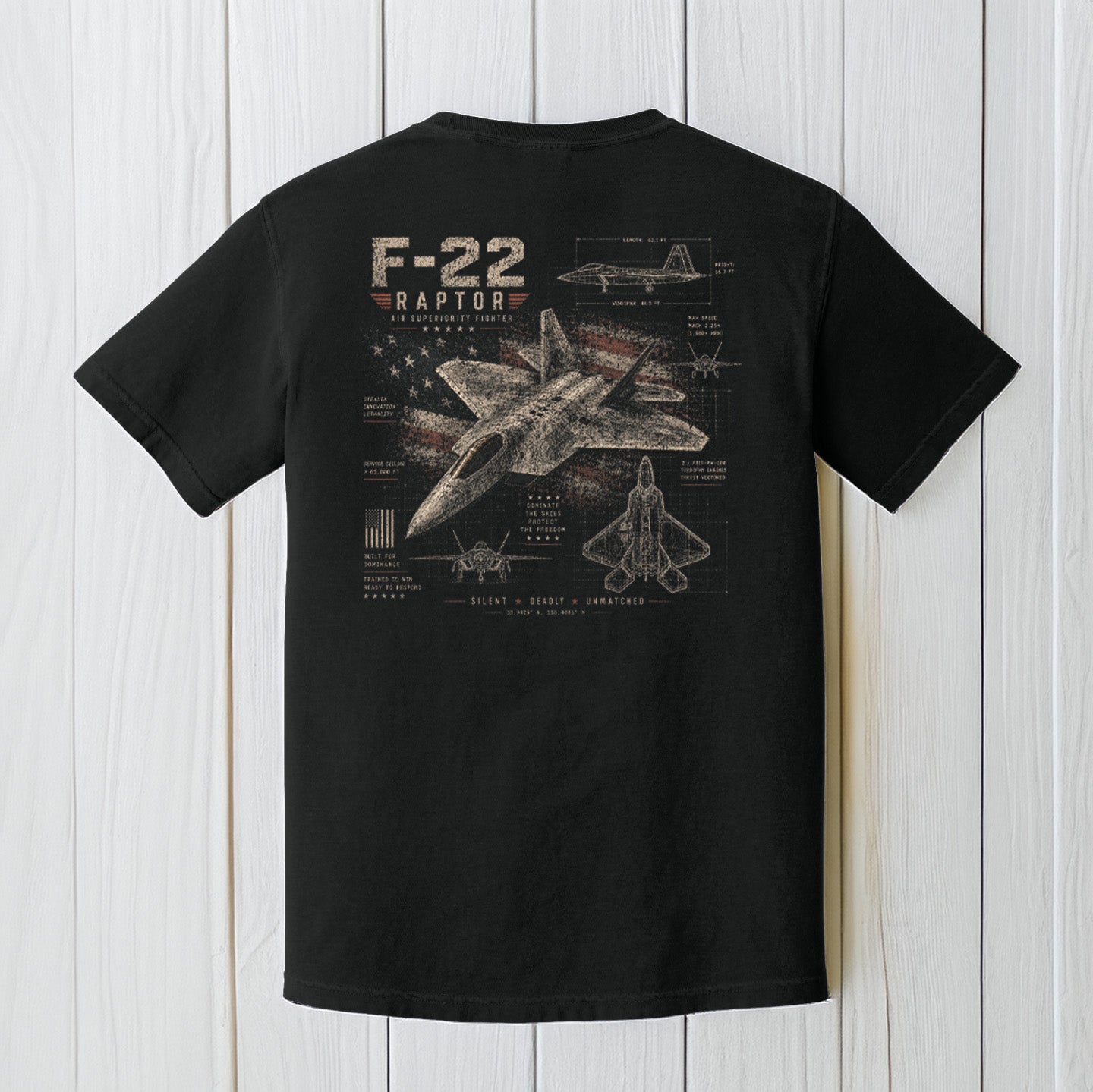 Black Comfort Colors F-22 Raptor t-shirt displayed on a white wood background.