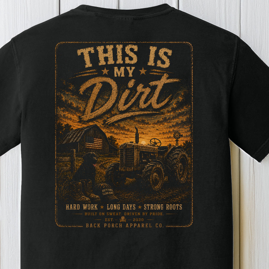 Distressed farm graphic featuring a tractor, farmer, dirt road, and rustic barn at sunset on a black Comfort Colors shirt.