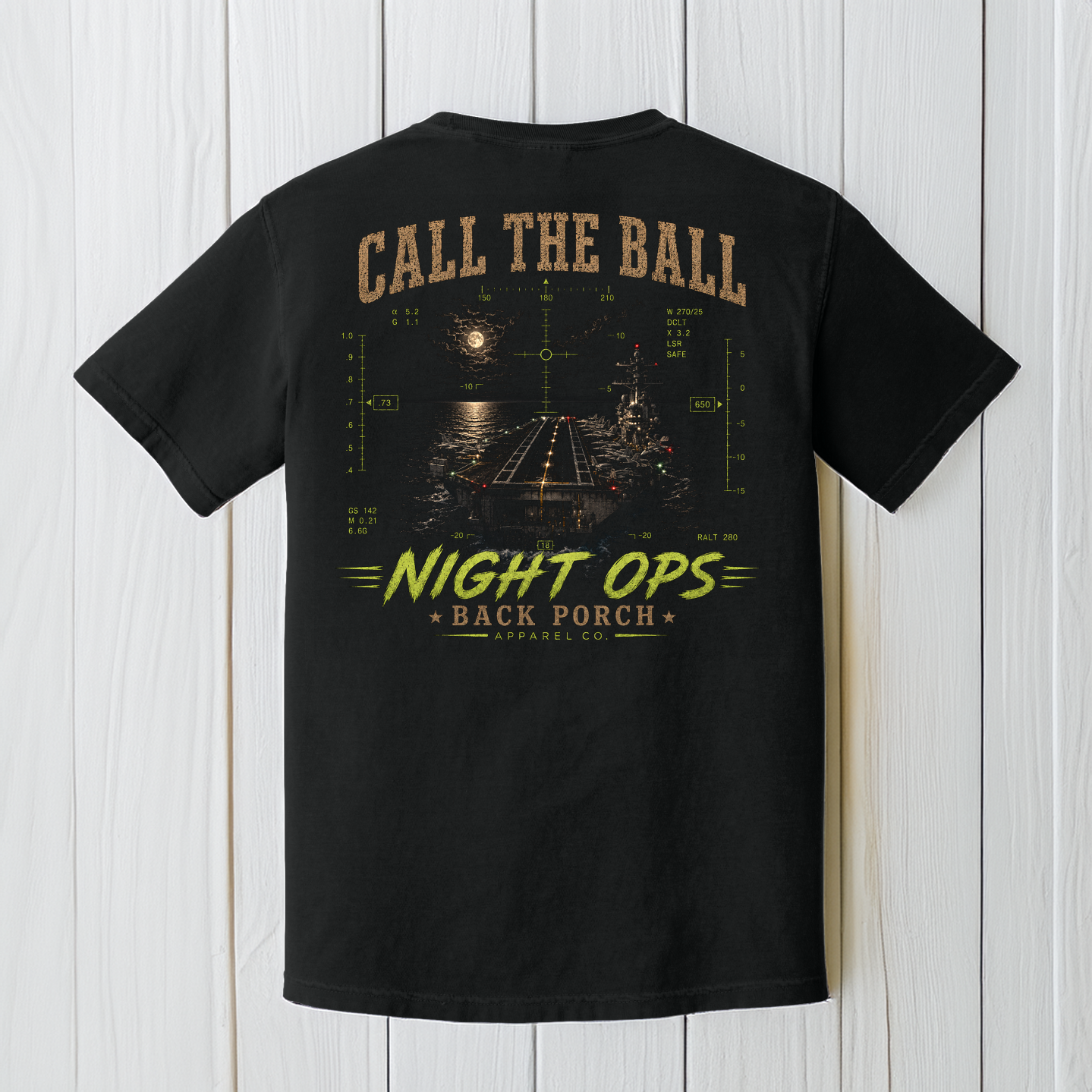 Black Comfort Colors aircraft carrier Night Ops t-shirt displayed on a white wood background featuring a nighttime carrier landing design.