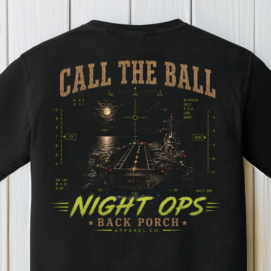 Close-up of the Call the Ball Night Ops graphic showing a moonlit aircraft carrier flight deck, HUD symbology, and military aviation artwork on a Black Comfort Colors t-shirt.