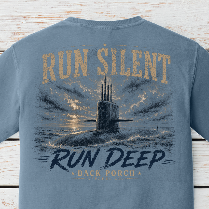 Close-up of the Run Silent Run Deep submarine artwork on a Blue Jean Comfort Colors t-shirt featuring a submarine beneath dramatic skies.