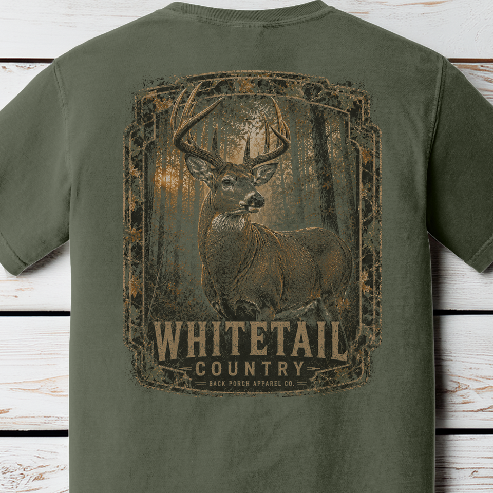 Close-up of the Whitetail Country trophy whitetail buck woodland artwork printed on a Comfort Colors Moss shirt.