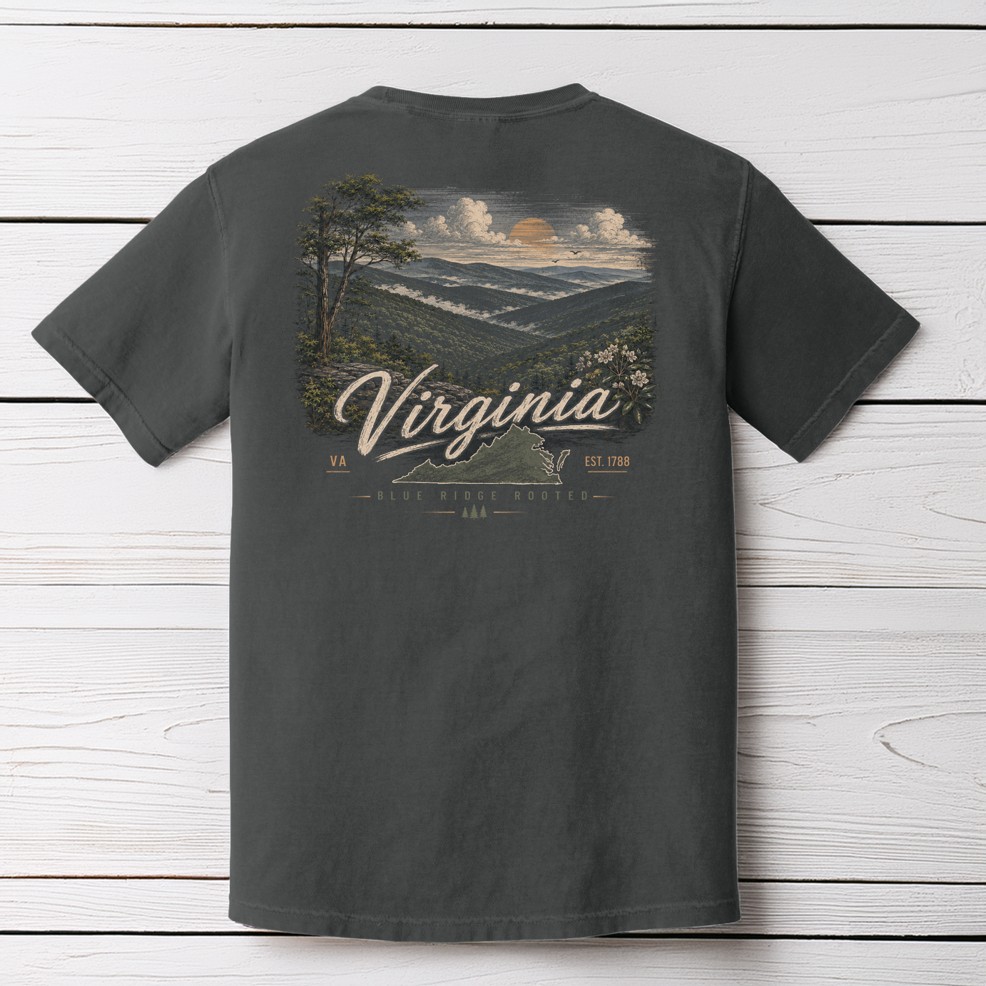 Pepper Comfort Colors Virginia Blue Ridge Rooted t-shirt displayed on a white wood background with scenic mountain artwork.