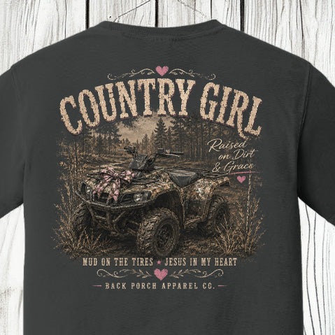 Distressed southern country girl graphic featuring a camouflage ATV, rustic woodland background, pink bow accents, and “Raised on Dirt & Grace” typography on a Comfort Colors shirt.