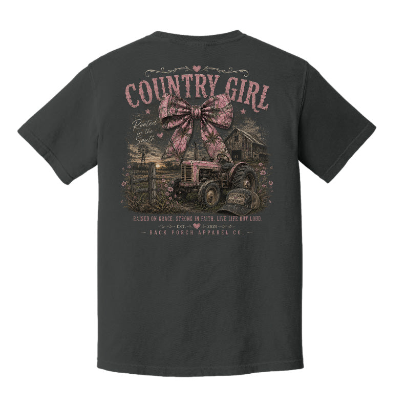 Back view of a Pepper Comfort Colors t-shirt displayed on a white background featuring a distressed country girl tractor graphic with pink bow accents and rustic farmhouse artwork by Back Porch Apparel.