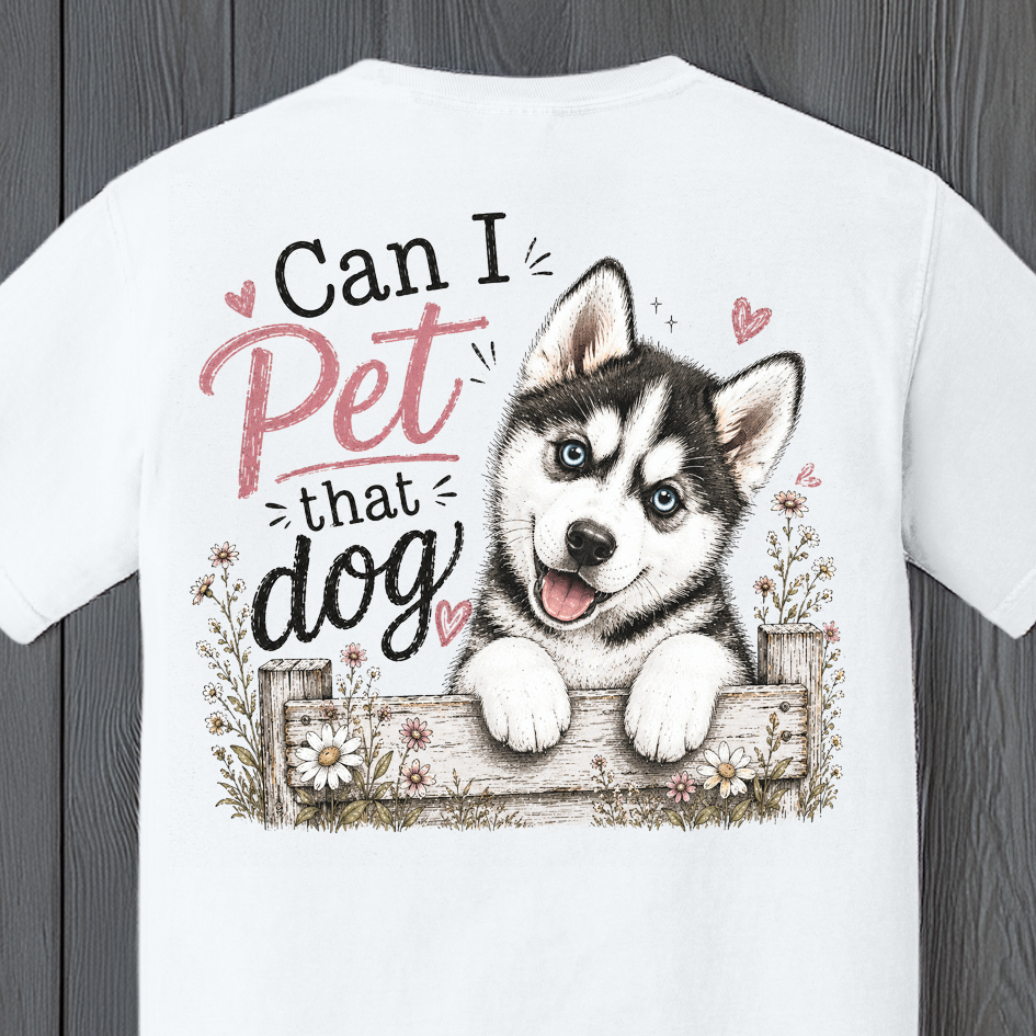 Close-up of the "Can I Pet That Dog" husky graphic featuring a happy blue-eyed Siberian Husky puppy peeking over a rustic fence with wildflowers and playful typography.
