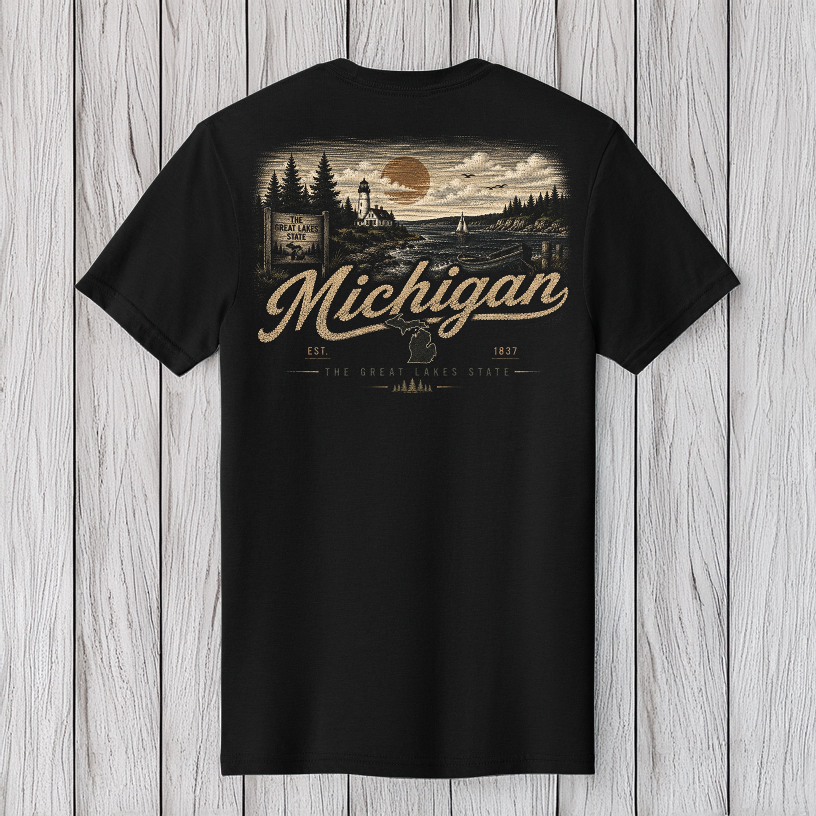 A black short-sleeve t-shirt with a vintage-style back graphic featuring a Michigan landscape, a large moon, and the text 'Michigan' and 'The Great Lakes Coast'. The shirt is displayed flat against a light gray wood plank background.