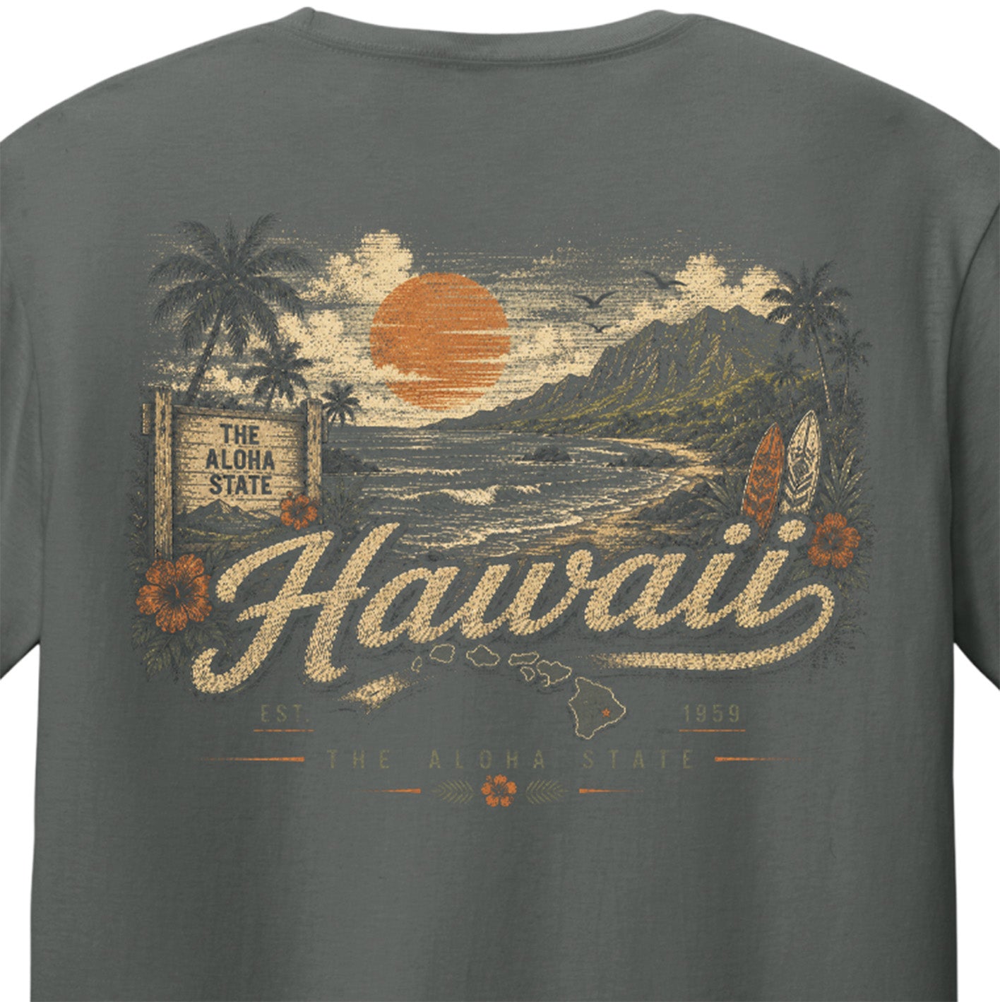 A close-up of a dark gray t-shirt showing the back graphic print. The print features a vintage-style Hawaiian beach scene with palm trees, a large orange sun, mountains, and the word 'Hawaii' in a textured cream font.