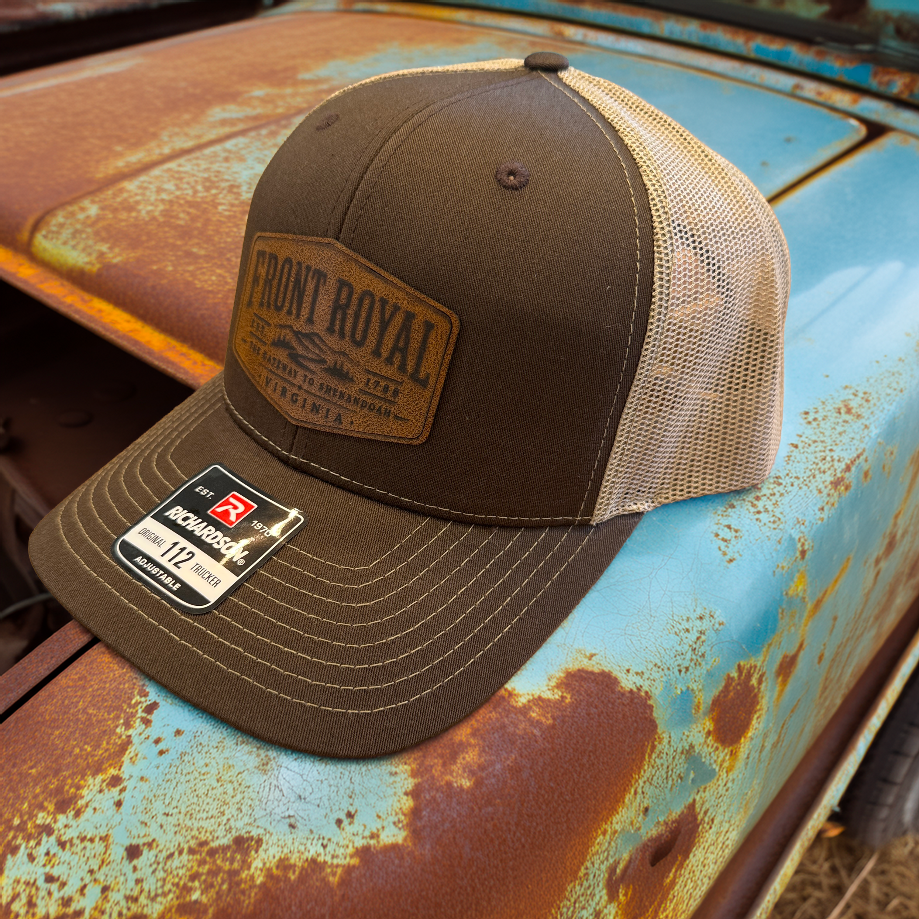 Front Royal Virginia leather patch Richardson 112 trucker hat displayed on the hood of a vintage rusted pickup truck.