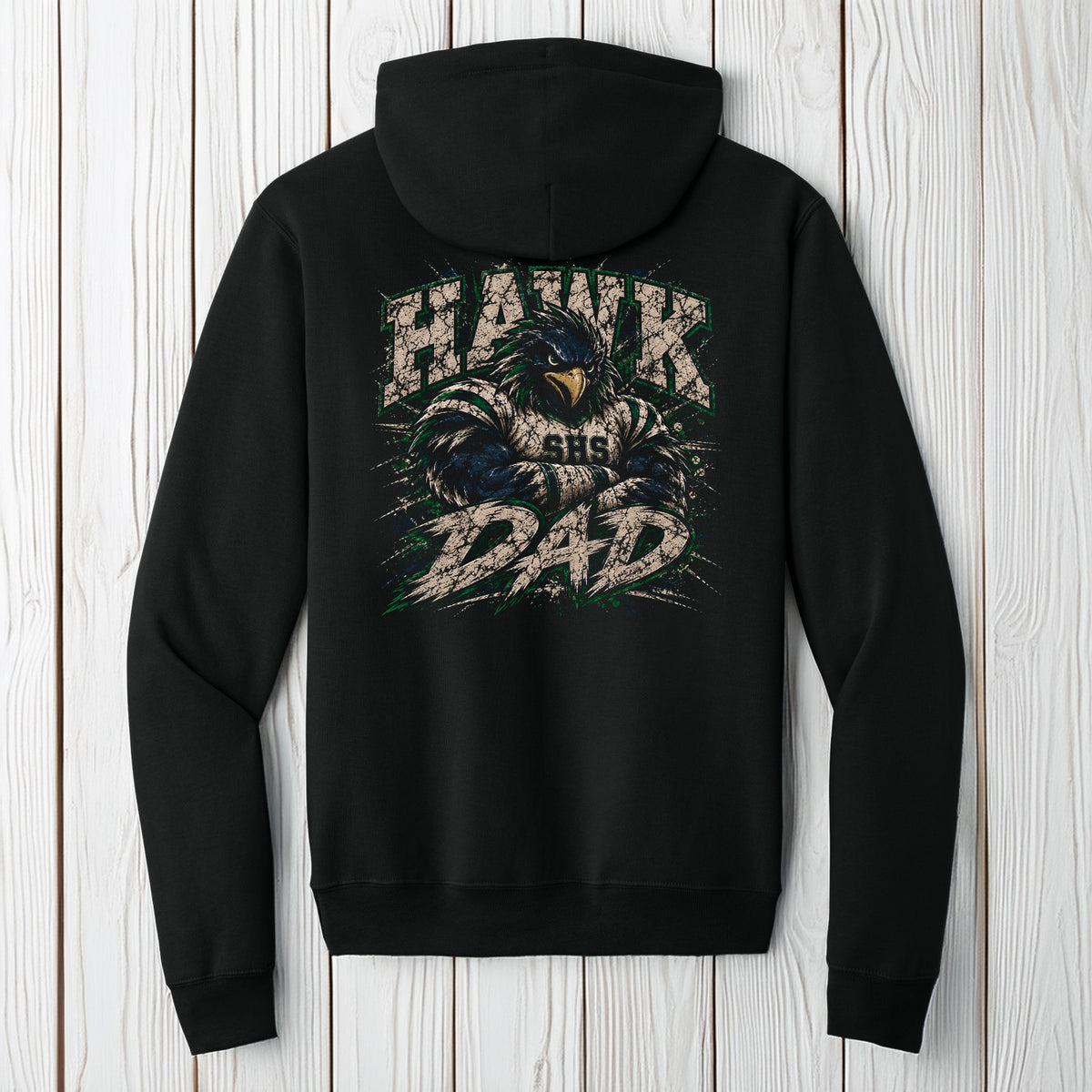 A black pullover hoodie shown from the back, featuring a large graphic print of a hawk with the text 'HAWK DAD' and 'CHG' on the back, displayed against a light gray wood plank background.