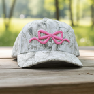 Simply Southern white camouflage trucker hat featuring an embroidered pink bow design on the front