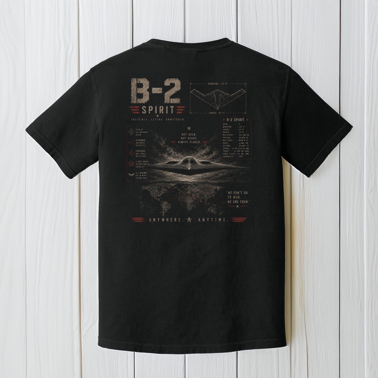 Black Comfort Colors B-2 Spirit stealth bomber t-shirt displayed on a white wood background.