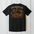 Black Comfort Colors Bigfoot crawfish boil t-shirt displayed on a white wood background featuring Low Country Life artwork.