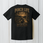 Black Comfort Colors dog lover graphic t-shirt displayed on a white wood background featuring two dogs overlooking a country sunset from a front porch.