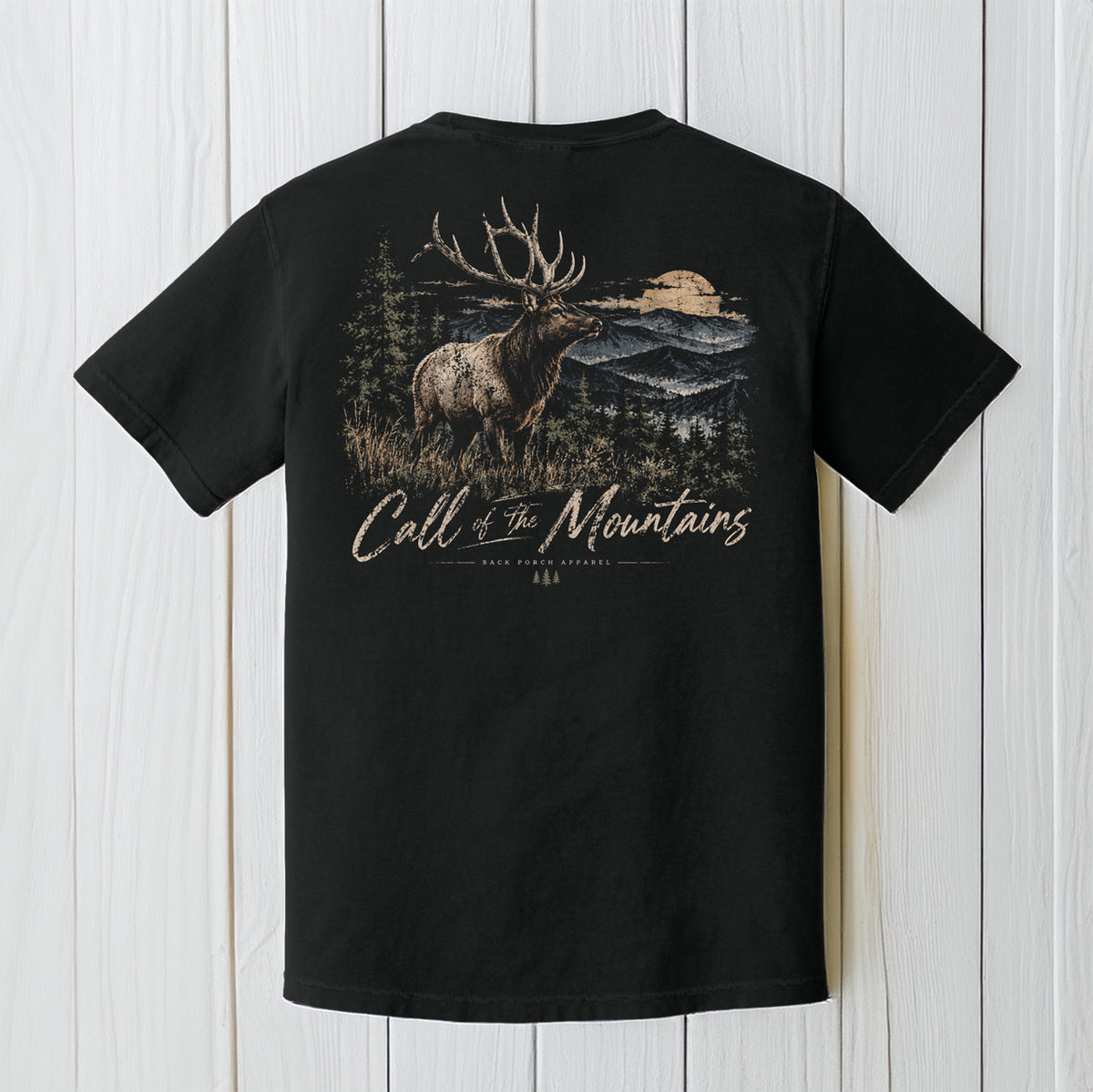 A black short-sleeve t-shirt shown from the back, featuring a large graphic print of a moose in a mountain landscape with the text 'Call of The Mountains' and 'Rocky Mountain National Park' on a white wood plank background.