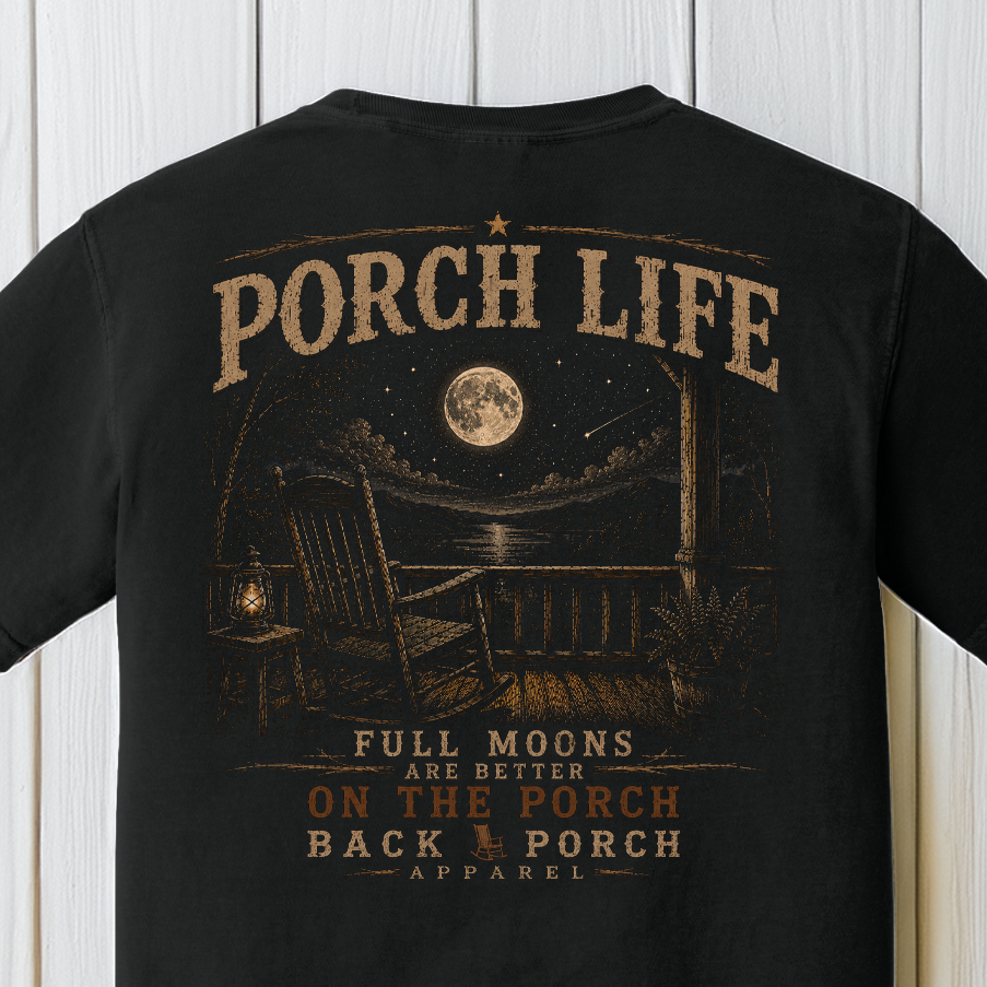 Close-up of the Porch Life Full Moons Are Better on the Porch artwork showing a rocking chair, glowing lantern, full moon, and rustic nighttime porch on a Black Comfort Colors t-shirt.