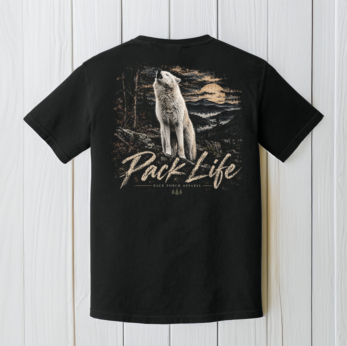A black short-sleeve t-shirt shown from the back, featuring a large graphic print of a howling wolf in a forest at sunset with the text 'Pack Life' and '4x4 POWER MEASURES'. The shirt is displayed flat against a white vertical wood plank background.