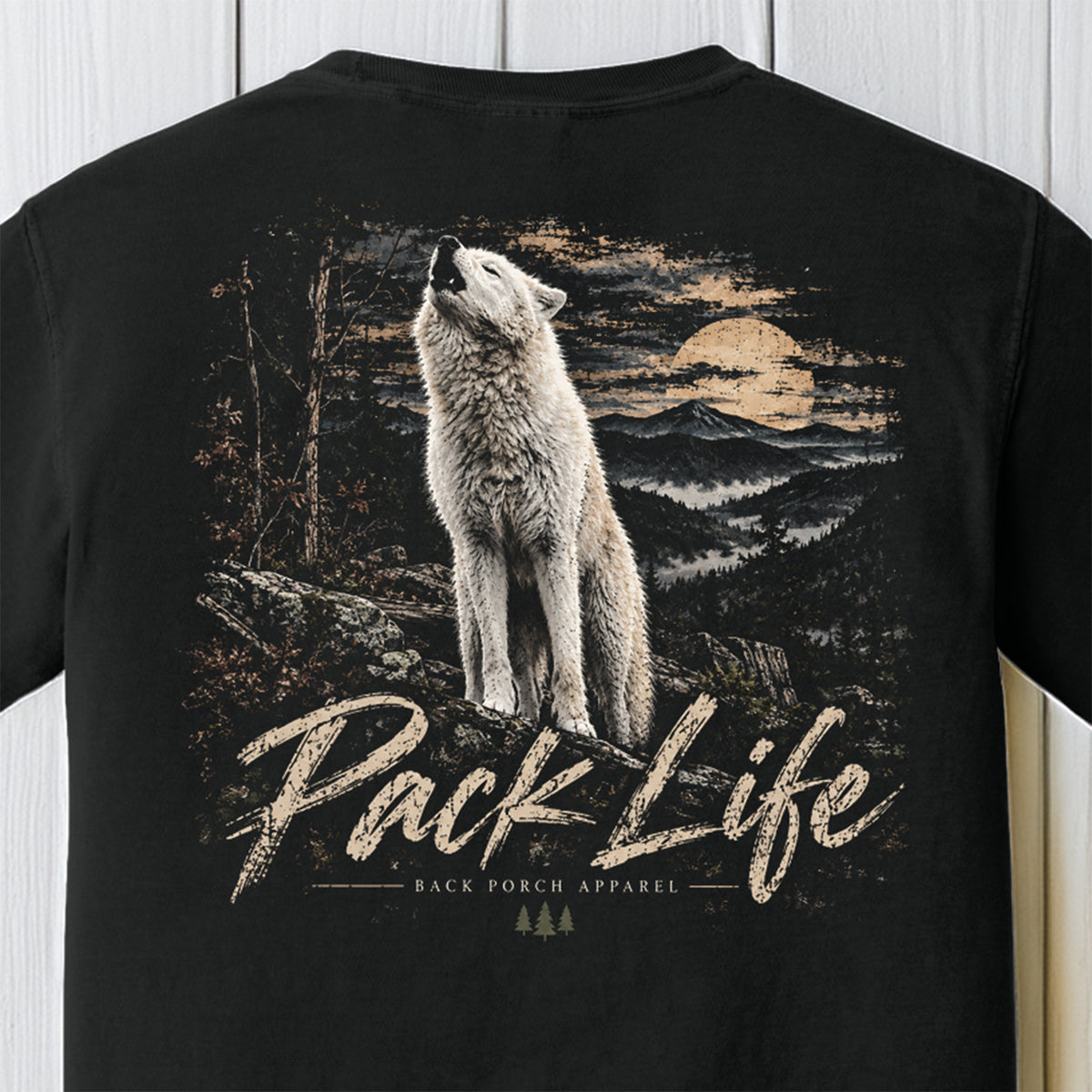 Black short-sleeve t-shirt featuring a large graphic print of a white wolf howling at a sunset over a mountain landscape, with the text 'Pack Life' and 'BACK FORCH APPAREL' printed below.