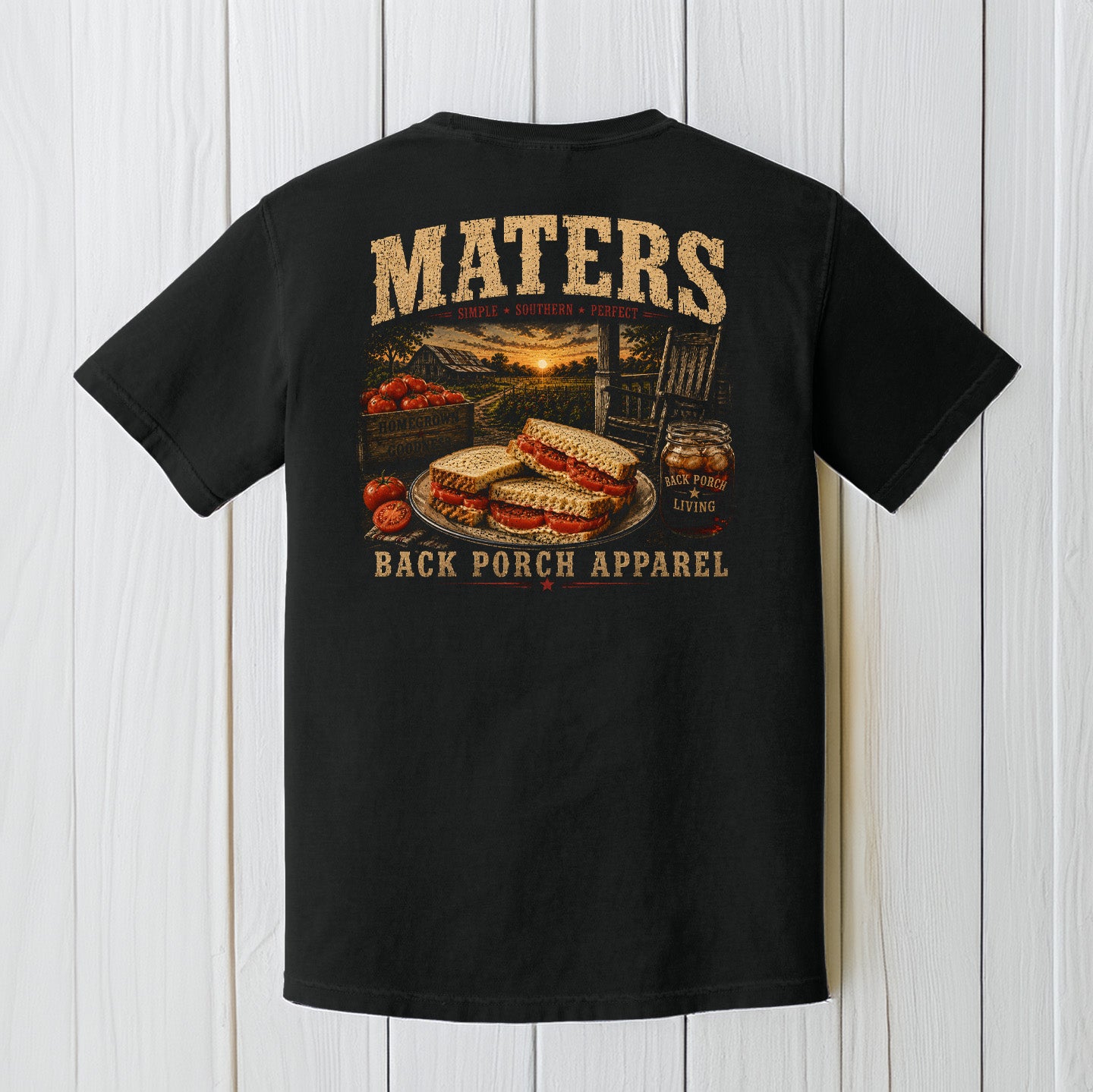 Black Comfort Colors t-shirt hanging on a wood background featuring a rustic southern tomato sandwich and porch life graphic design.