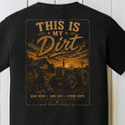 Distressed farm graphic featuring a tractor, farmer, dirt road, and rustic barn at sunset on a black Comfort Colors shirt.