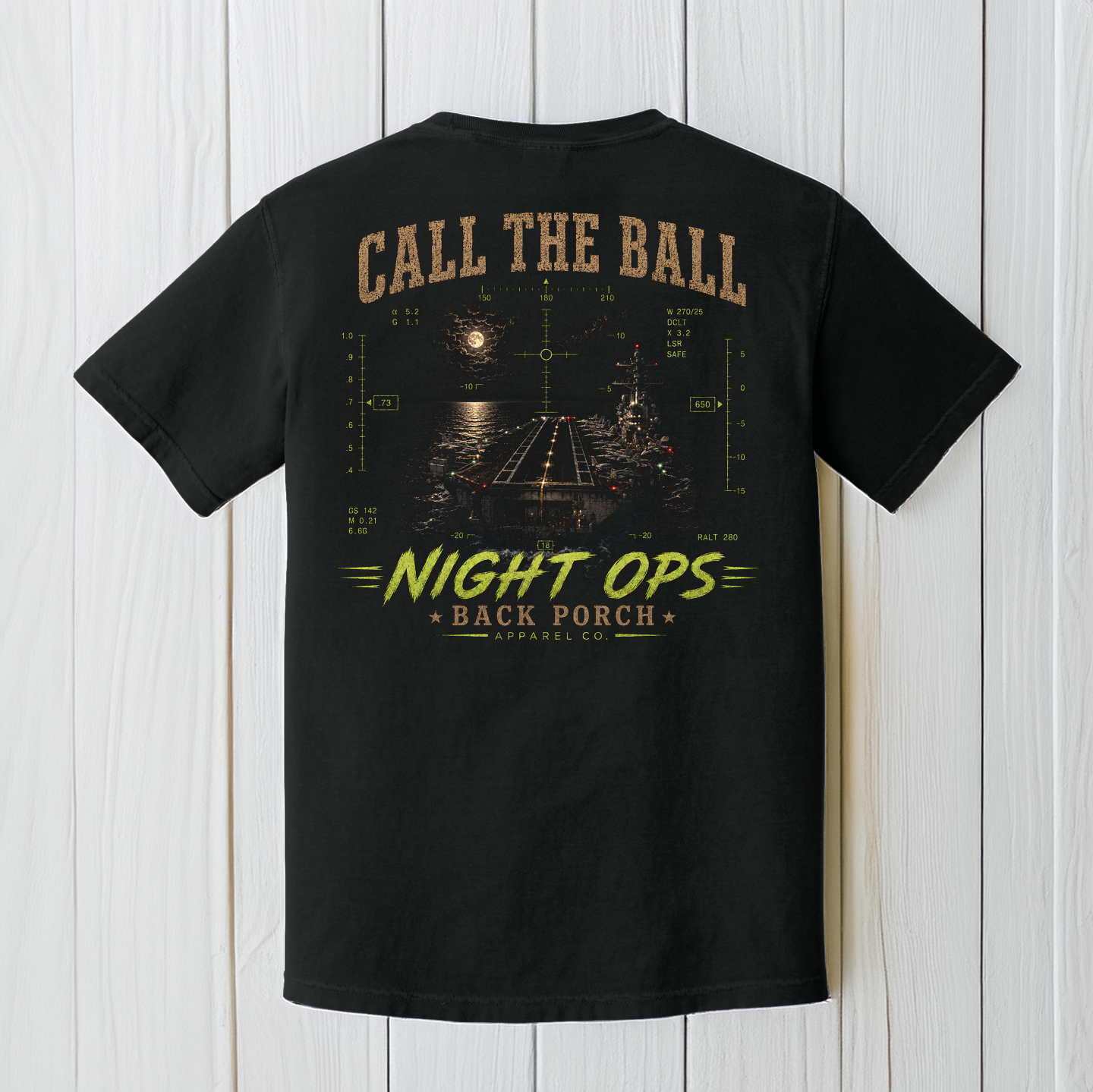 Black Comfort Colors aircraft carrier Night Ops t-shirt displayed on a white wood background featuring a nighttime carrier landing design.