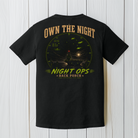 Black Comfort Colors aircraft carrier graphic t-shirt displayed on a white wood background featuring the Night Ops military aviation design.