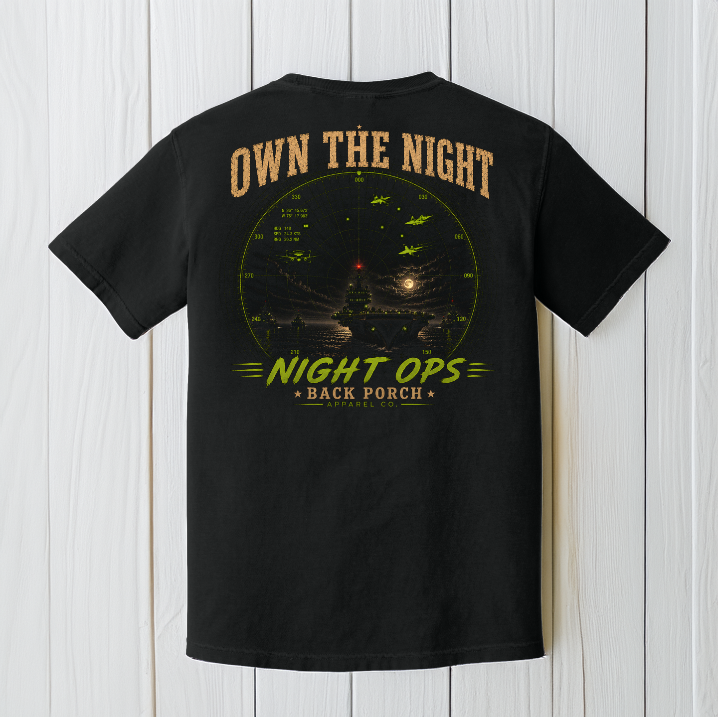 Black Comfort Colors aircraft carrier graphic t-shirt displayed on a white wood background featuring the Night Ops military aviation design.