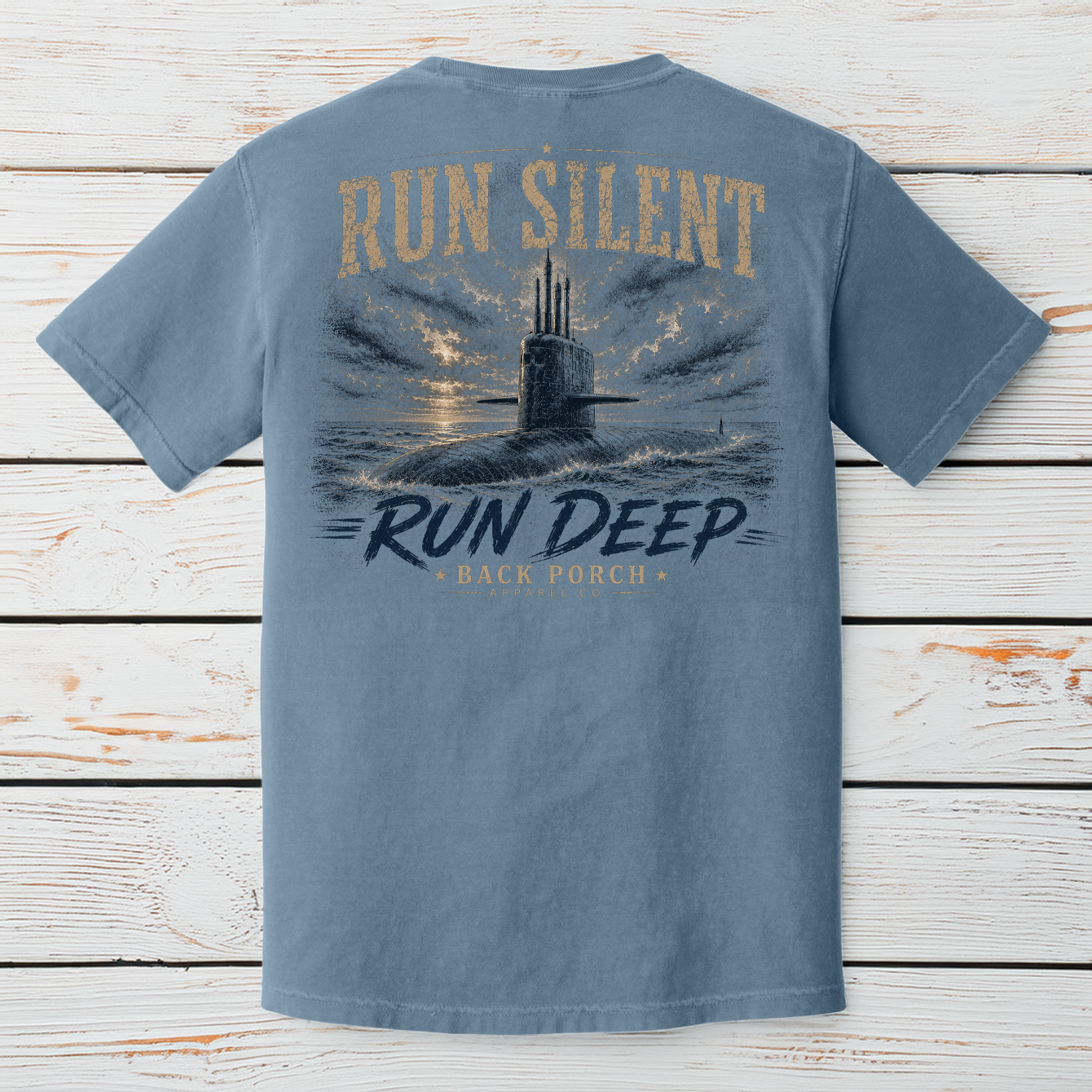 Blue Jean Comfort Colors submarine graphic t-shirt displayed on a white wood background featuring the Run Silent Run Deep design.