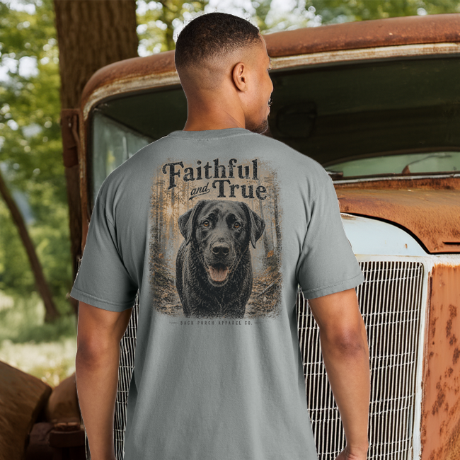 Man wearing the Faithful and True black Labrador Comfort Colors Grey t-shirt beside a vintage pickup truck outdoors.