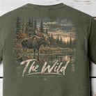 An olive green t-shirt showing the back graphic print with a moose in a forest by a river and the text 'The Wild' and 'Back Forch Apparel'.