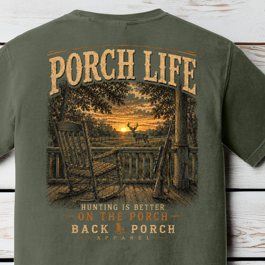 Distressed hunting porch graphic featuring a rocking chair, rifle, sunset deer scene, and “Hunting Is Better on the Porch” typography on a Comfort Colors Moss shirt.