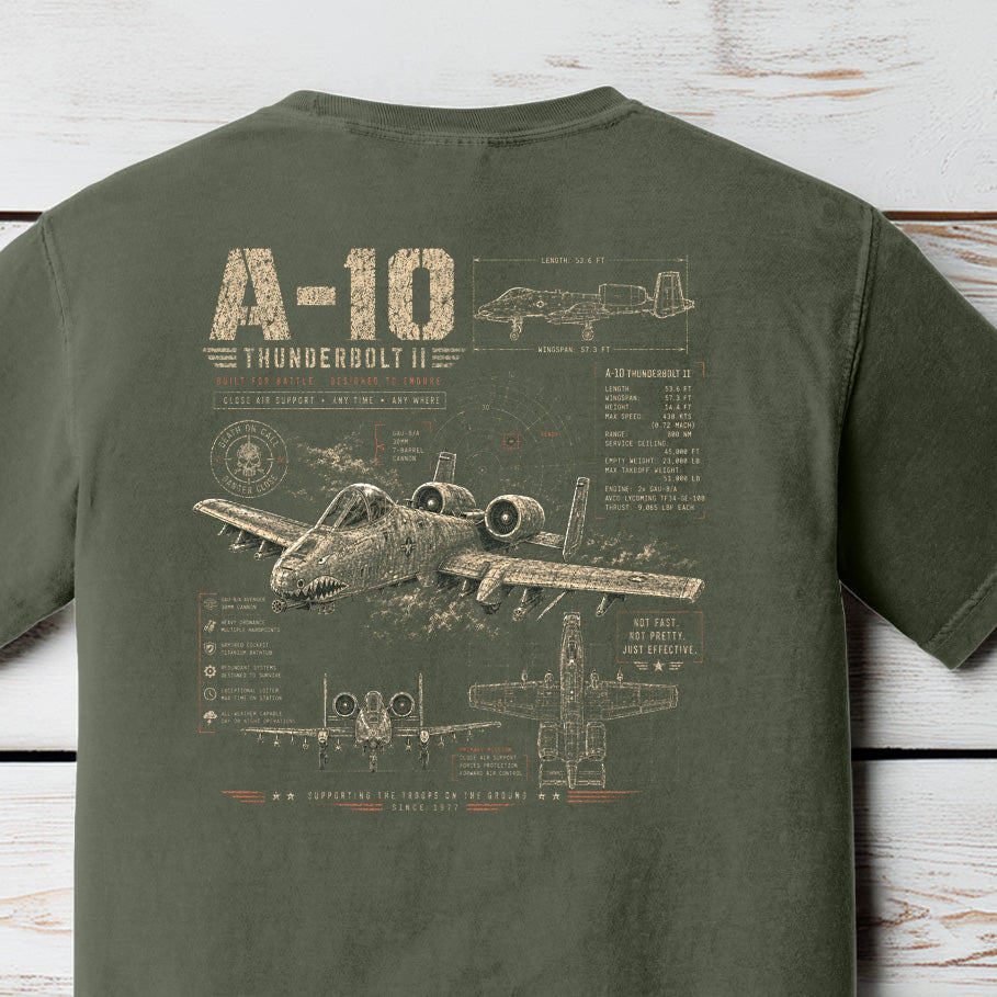 Distressed A-10 Thunderbolt II military aircraft blueprint graphic featuring detailed schematics and tactical aviation artwork on a Comfort Colors Moss shirt.
