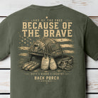 Distressed patriotic military graphic featuring a tactical combat helmet, dog tags, gloves, and American flag artwork on a Comfort Colors Moss shirt.