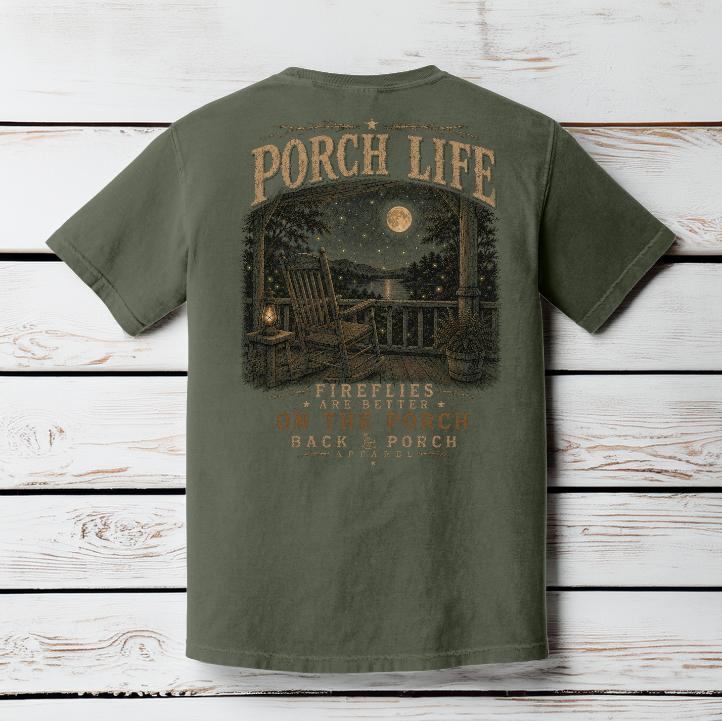 Moss Comfort Colors Porch Life graphic t-shirt displayed on a wood background featuring a peaceful porch scene with a full moon and glowing fireflies.