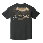 A dark charcoal gray t-shirt shown from the back, featuring a large vintage-style graphic of a mountain cabin under a sunset sky with the text 'Gatlinburg' and 'Est. 1845'.