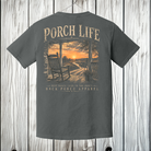 Pepper Comfort Colors Porch Life graphic t-shirt displayed against a rustic wood background featuring a peaceful country porch at sunset.