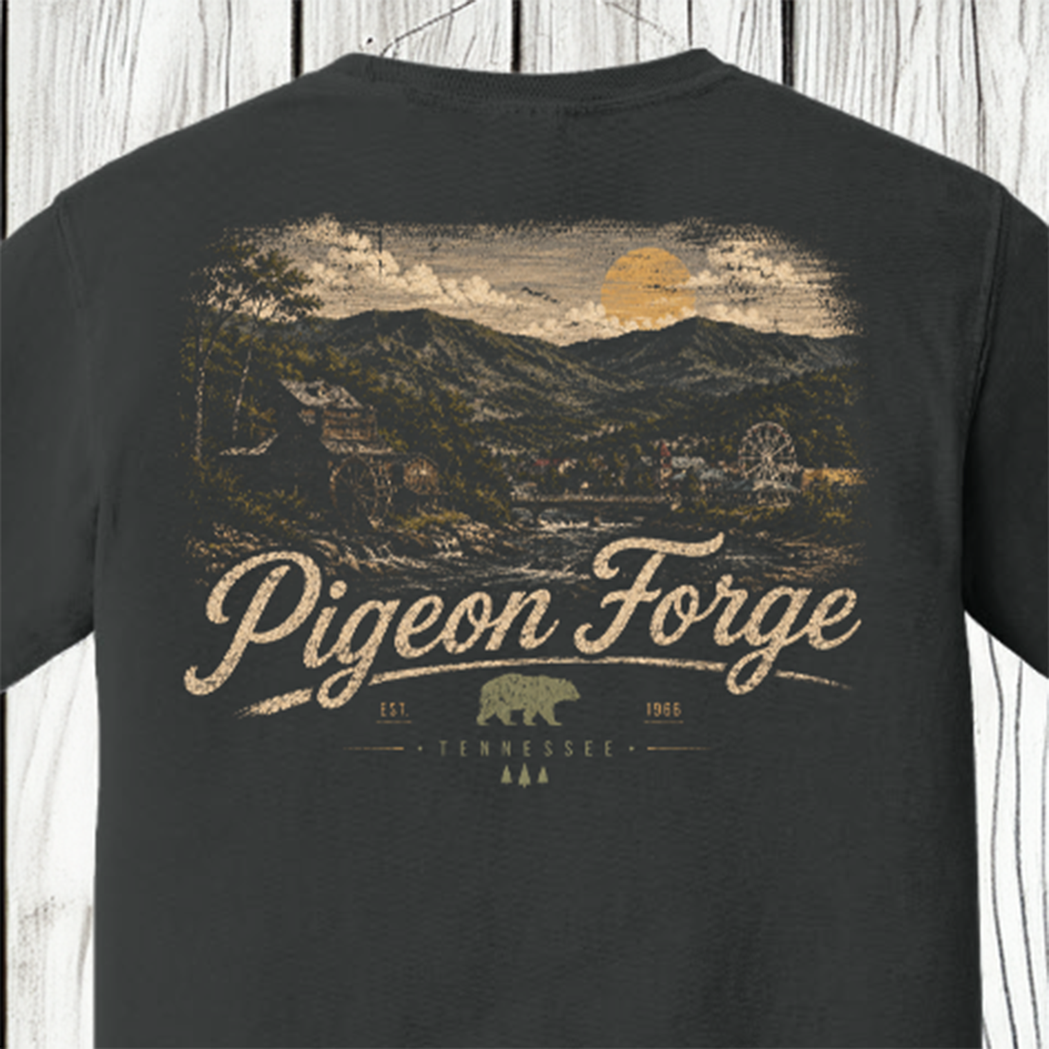A dark charcoal gray t-shirt shown from the back, featuring a large vintage-style graphic print of a Tennessee landscape with mountains, a river, and a sun, with the text 'Pigeon Forge' and 'TENNESSEE' printed below.