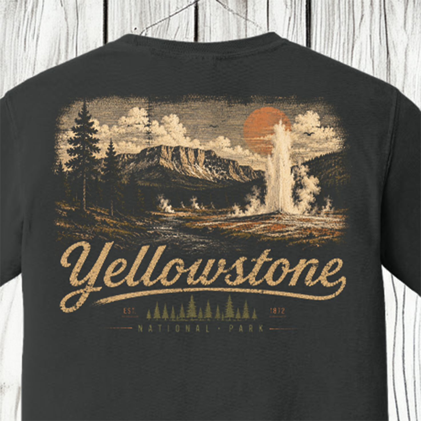 A dark charcoal gray t-shirt featuring a vintage-style Yellowstone National Park graphic on the front. The graphic depicts a geyser erupting from a mountain under a large orange sun, with 'Yellowstone' and 'National Park' written in a distressed beige font below.