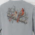 A light gray long-sleeve crewneck sweatshirt featuring a large graphic print of two red cardinal birds perched on a flowering branch with a snowy forest background.