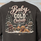 Close-up of Baby It’s Cold Outside winter shirt design with golden retriever, campfire, Adirondack chairs, snowy pines and mountains