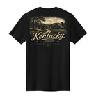 A black short-sleeve t-shirt shown from the back, featuring a vintage-style graphic of a Kentucky landscape with a winding road, trees, hills, and a barn, with 'Kentucky' written in large script across the center.