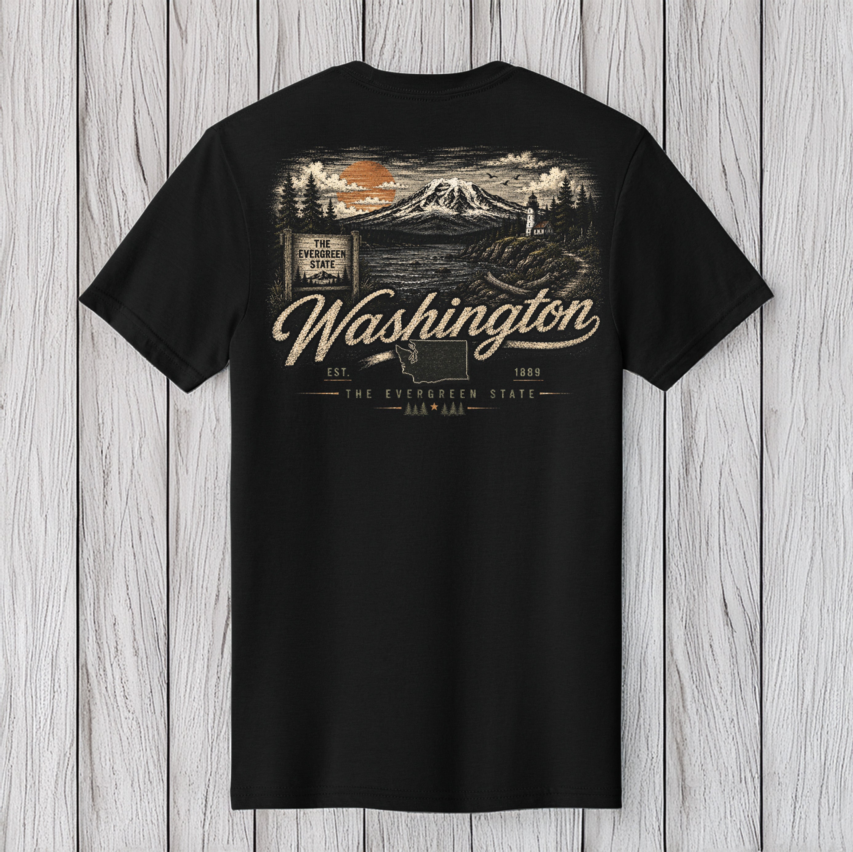 A black short-sleeve t-shirt with a detailed graphic print on the back, featuring a mountain landscape, a mountain sign, and the text 'Washington' in a cursive font, displayed against a light gray wood plank background.