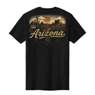 A black short-sleeve t-shirt shown from the back, featuring a detailed desert landscape graphic in tan and brown tones with the word 'Arizona' in large script across the center.