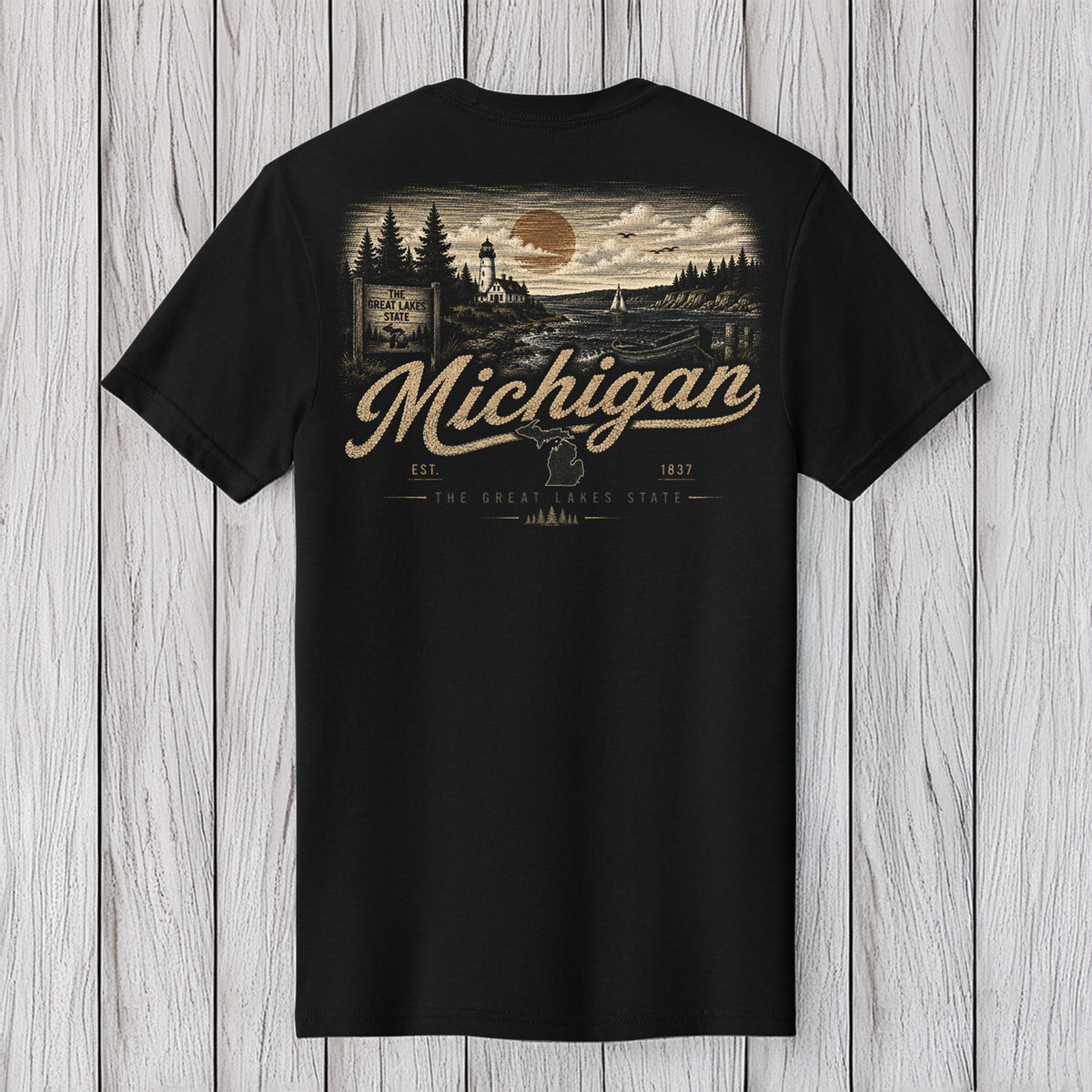 A black short-sleeve t-shirt with a vintage-style back graphic featuring a Michigan landscape, a large moon, and the text 'Michigan' and 'The Great Lakes Coast'. The shirt is displayed flat against a light gray wood plank background.