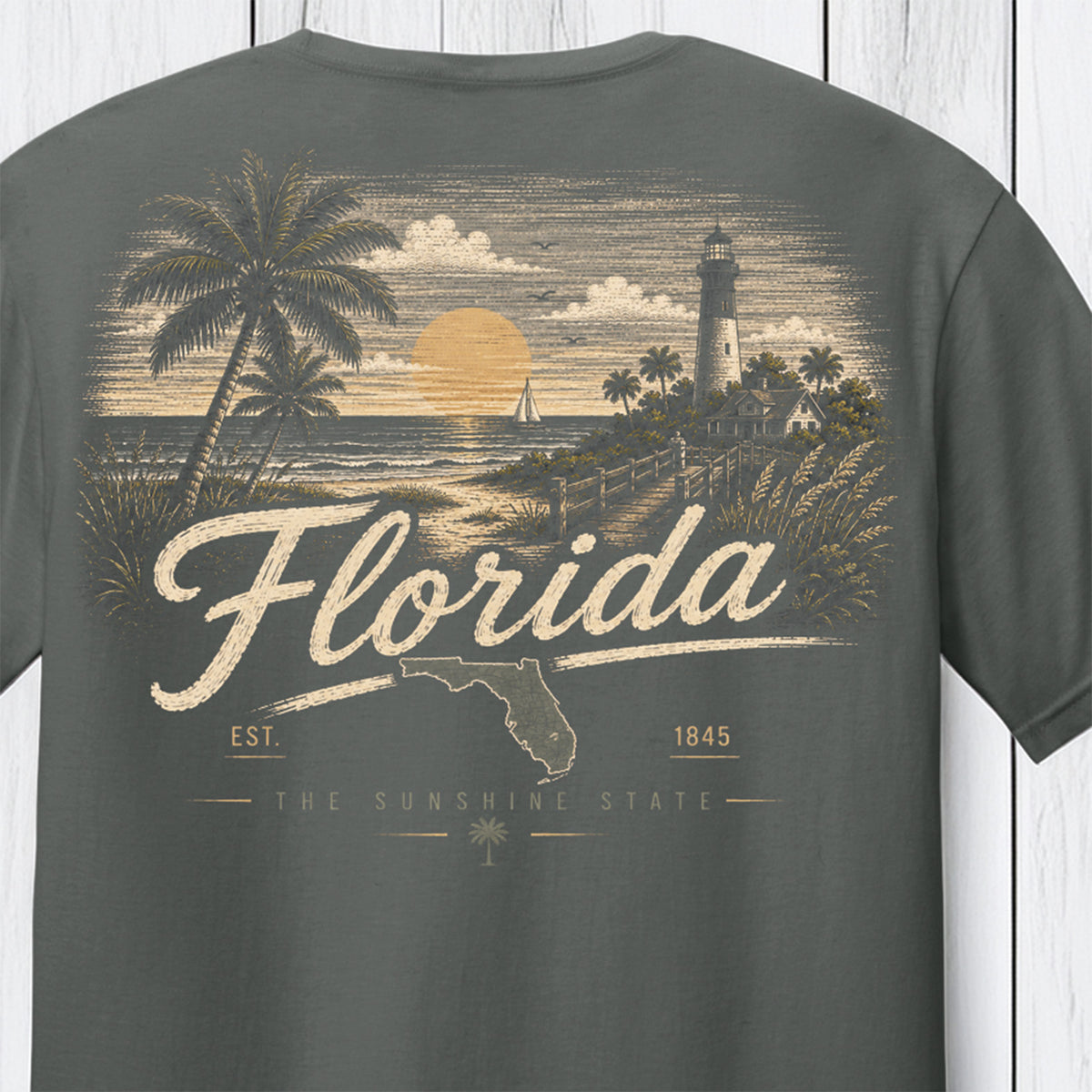 A dark gray t-shirt showing the back graphic print with a vintage Florida theme, featuring a lighthouse, palm trees, a sunset, and the text 'Florida' and 'The Sunshine State'.