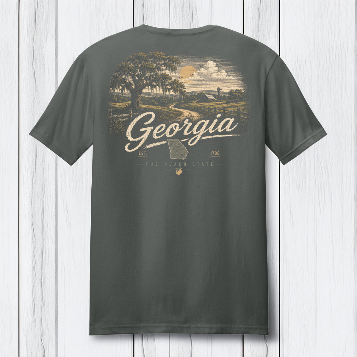 A dark gray t-shirt shown from the back, featuring a vintage-style graphic of a Georgia landscape with a tree, country road, and clouds, with 'Georgia' written in script across the center.