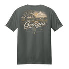 A dark gray crewneck t-shirt shown from the back, featuring a large graphic print of a Georgia landscape with a tree, fields, and the text 'Georgia' and 'The Peach State' in cream and light brown tones.