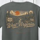 A dark gray t-shirt featuring a vintage-style West Virginia graphic print with an orange sun, bridge, trees, and the words 'West Virginia' and 'The Mountain State'.