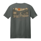 A dark gray t-shirt showing the back side with a large vintage-style graphic print of a West Virginia landscape, featuring an orange sun, river, bridge, and 'West Virginia' text.